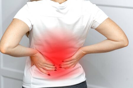 Closeup view of young women with back pain in the muscles which is caused by heavy lifting, the concept of musculoskeletal system.の写真素材