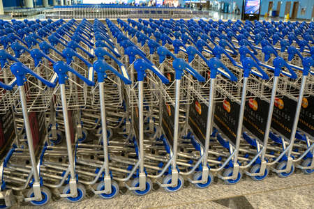 Ufa, Russia april 2, 2020: Airport trolley parking lot with empty trolleys and blue wall. Luggage carts at modern airport.のeditorial素材