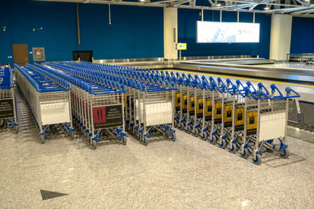 Ufa, Russia april 2, 2020: Airport trolley parking lot with empty trolleys and blue wall. Luggage...