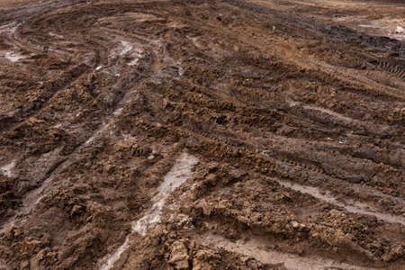 An impassable road, off-road track in autumn forest. Deep ruts in the slushy autumn road.