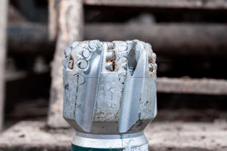 The drill bit, shot close-up with shallow depth of field. Industrial background. Tricone drilling...