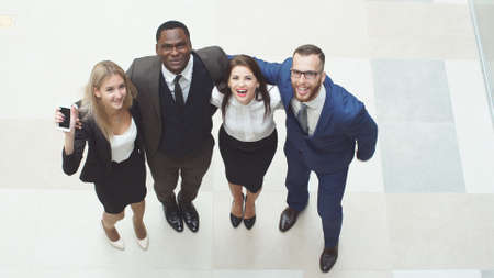Portrait of group of happy and diverse business people who are standing together. They jump in the air and cheer to celebrate their business success.の写真素材