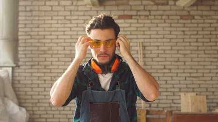 Portrait of Attractive Young Handsome Carpenter Leaned on The Table in Workshopの写真素材