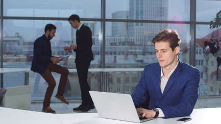 Businessman reading news on laptop computer at coworking space. Male professional making purchases...