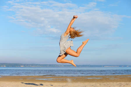 Beautiful young girl jumping on sea
