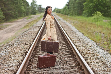 Young woman with a suitcase on the railsの写真素材