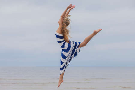 Young woman on the ocean shore in dress