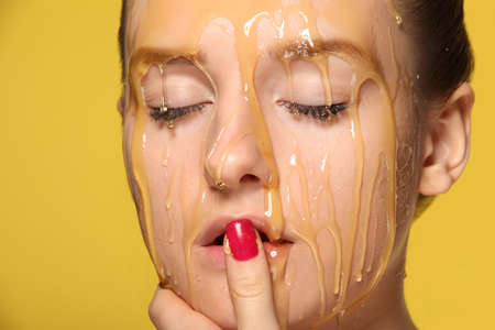 Beautiful young woman with honey on her faceの写真素材