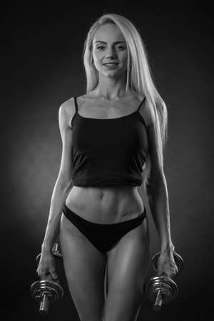 beautiful sporty muscular woman working out with dumbbellsの写真素材