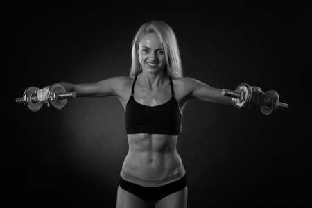 beautiful sporty muscular woman working out with dumbbellsの写真素材