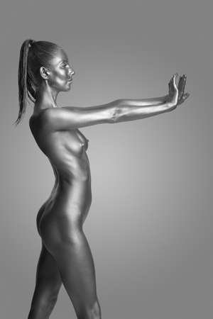 Beautiful naked slender girl posing on a gray backgroundの写真素材