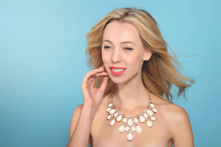 Portrait of beautiful young smiling woman on blue backgroundの写真素材