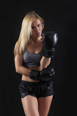 Girl in boxing gloves on a black backgroundの写真素材