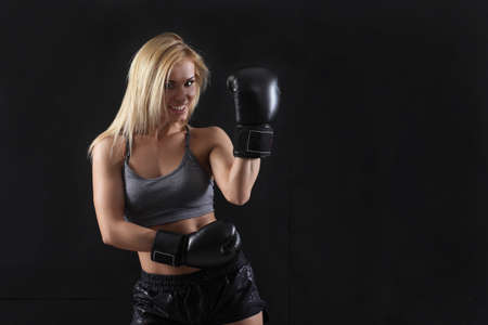 Girl in boxing gloves on a black backgroundの写真素材
