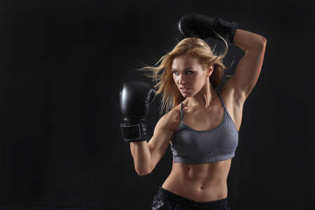 Girl in boxing gloves on a black backgroundの写真素材