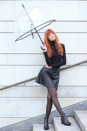 Young cute red-haired girl with an umbrellaの写真素材