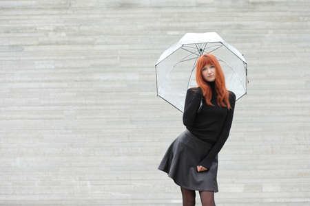 Young cute red-haired girl with an umbrellaの写真素材