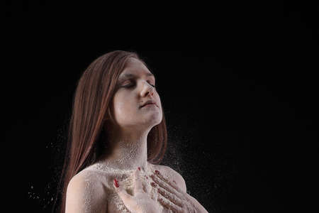portrait of a young girl in flour on a black backgroundの写真素材
