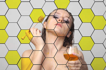 photo of a young girl with honeycomb and honey on her skinの写真素材