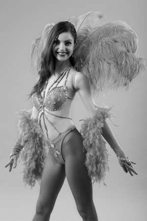 Young woman dancer in bikini and suit with feathers
