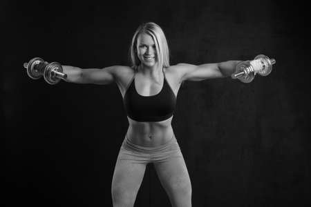 Young sporty slim muscular girl with dumbbellsの写真素材