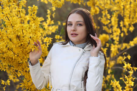 Young cute girl posing at the bush with spring flowers