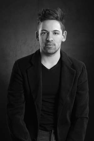 young stylish solid man in a blazer against a dark backgroundの写真素材