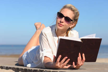 young woman reads a book on the beachの写真素材