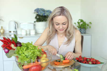 beauty young positive smiling woman with vegetables in the kitchen