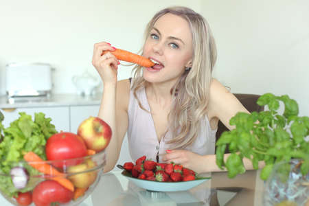 beauty young positive smiling woman with vegetables in the kitchen