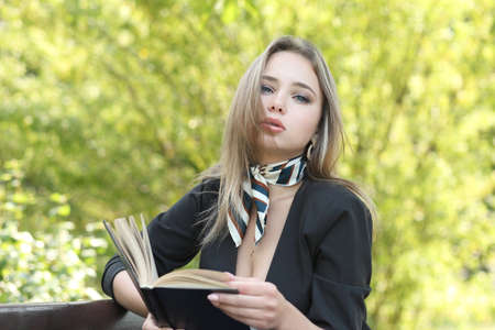 young girl in park reads a book