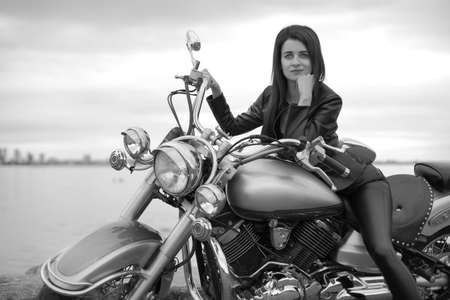young beautiful girl in black with a motorcycle