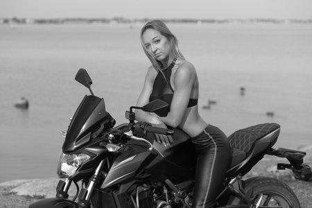 young woman with a sports motorcycle on sea backgroundの写真素材