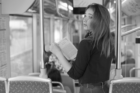 Beautiful young woman in tram reading her bookの写真素材