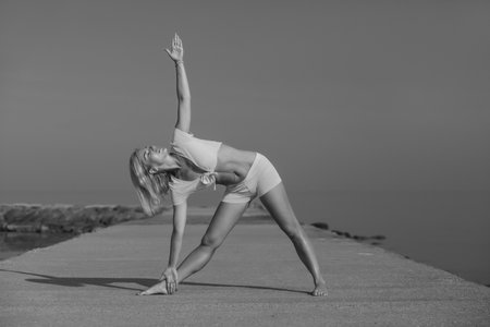 young athletic healthy girl doing yoga by the seaの写真素材