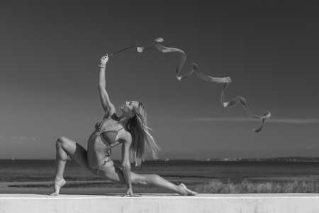 sports woman rhythmic gymnast with red ribbonの写真素材