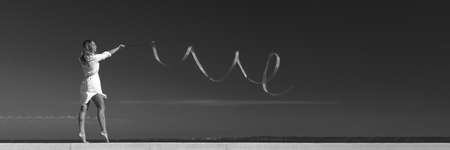 sports woman rhythmic gymnast with red ribbonの写真素材