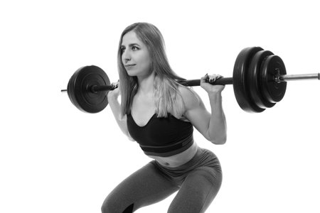 young strong girl raises the barbell on a black backgroundの写真素材