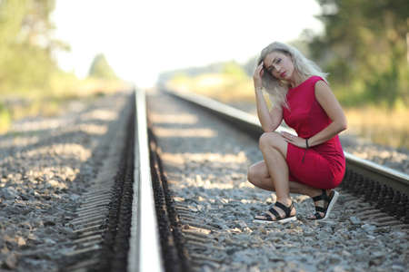young woman in red dress on the railwayの写真素材