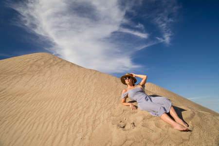 young woman on sandy mountain posing in dressの写真素材