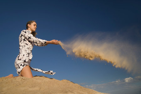 young woman on sandy mountain posing in dressの写真素材
