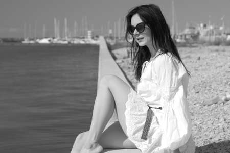 young slender woman by the sea posing in clothes