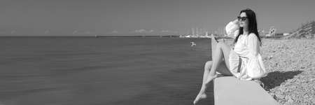 young slender woman by the sea posing in clothesの写真素材