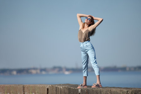 young slender woman by the sea posing in clothesの写真素材