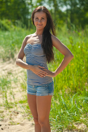 young slender woman by the sea posing in clothesの写真素材