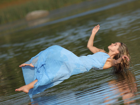 young slender woman by the sea posing in clothesの写真素材