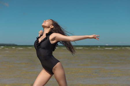 young graceful and flexible gymnast in swimsuit flexibility by the seaの写真素材
