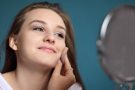 young girl applies cosmetics and looks in the mirrorの写真素材