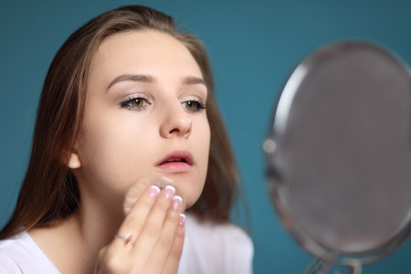 young girl applies cosmetics and looks in the mirrorの写真素材