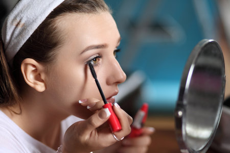 young girl applies cosmetics and looks in the mirrorの写真素材